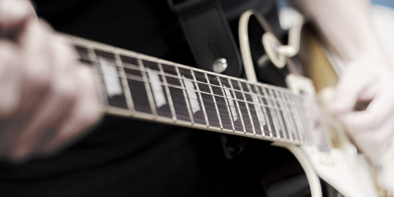 Left handed guitar being played, closeup of fingerboard
