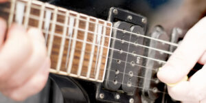 Left handed guitar being played, closeup of frets and neck pickup