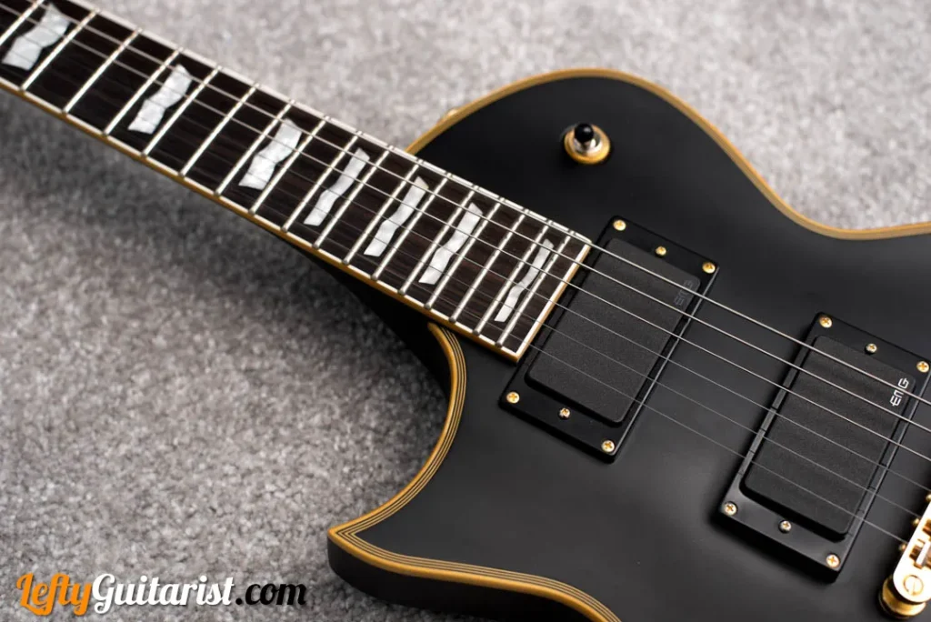 The body of a left handed ESP LTD EC-1000 in Vintage Black finish. Photo shows the fingerboard from the twelfth fret to the 24th, and two EMG pickups.