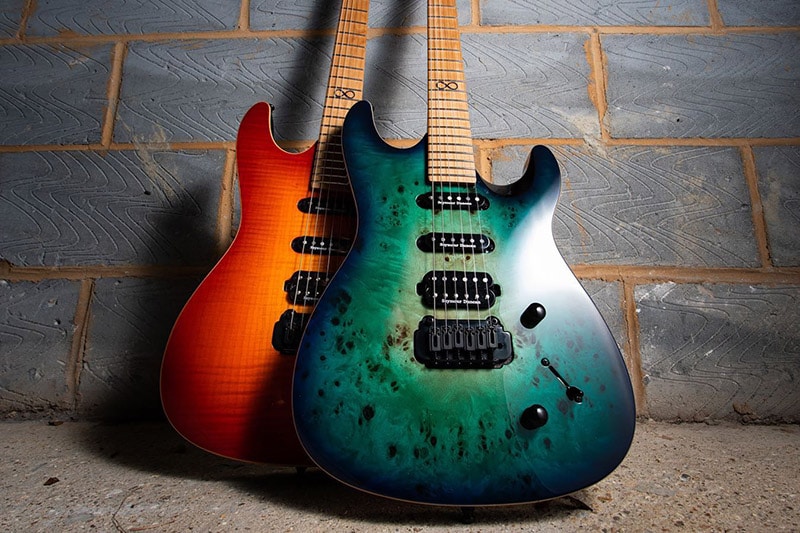 Two Chapman ML-1 Pro Hybrid guitars leaning against a wall. One with a Turquoise Rain finish stands in front of the other ML-1 Pro Hybrid with a Phoenix Rex finish.