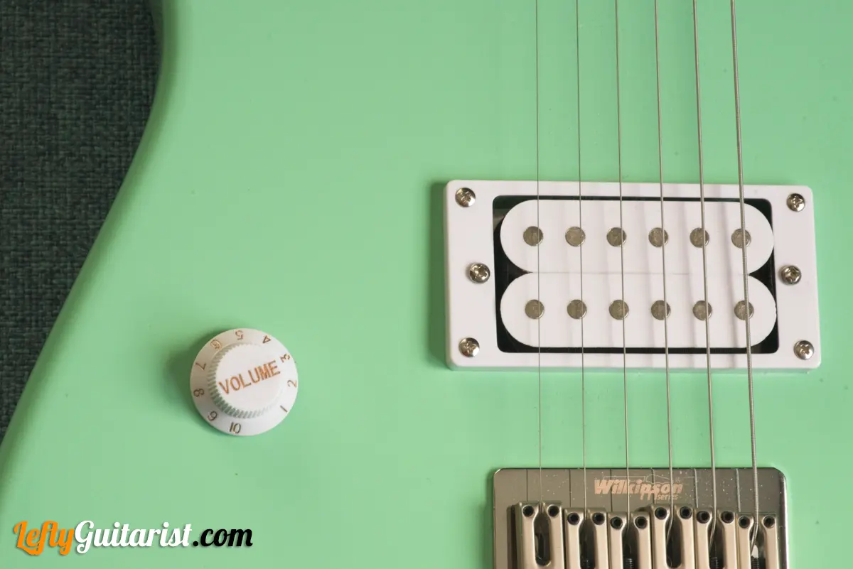 Photo of a left-handed Fazley Custom Series Hot Rod V2 Electric Guitar with Fixed Bridge in a Surf Green finish. Close-up of the volume knob and humbucker pickup.