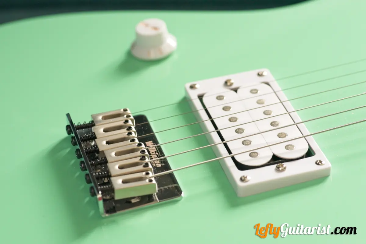Photo of a left-handed Fazley Custom Series Hot Rod V2 Electric Guitar with Fixed Bridge in a Surf Green finish. Close-up of the Wilkinson M-Series bridge.