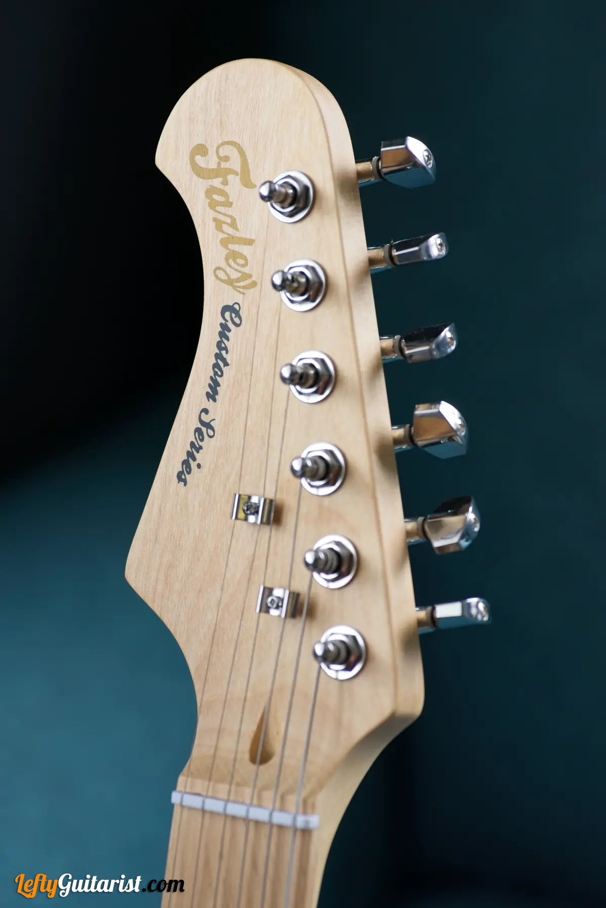 Photo of a left-handed Fazley Custom Series Hot Rod V2 Electric Guitar with Fixed Bridge in a Surf Green finish. Close-up of the headstock.